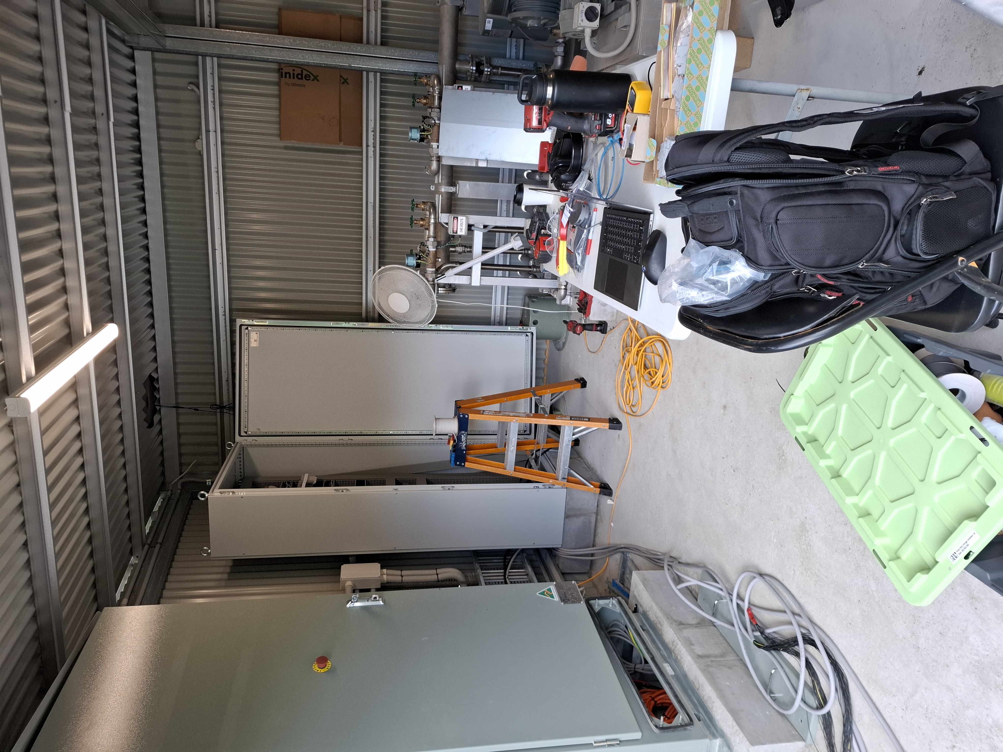 Plant room mid-commissioning — twin cabinet line-up, treatment skid and laptop on bench