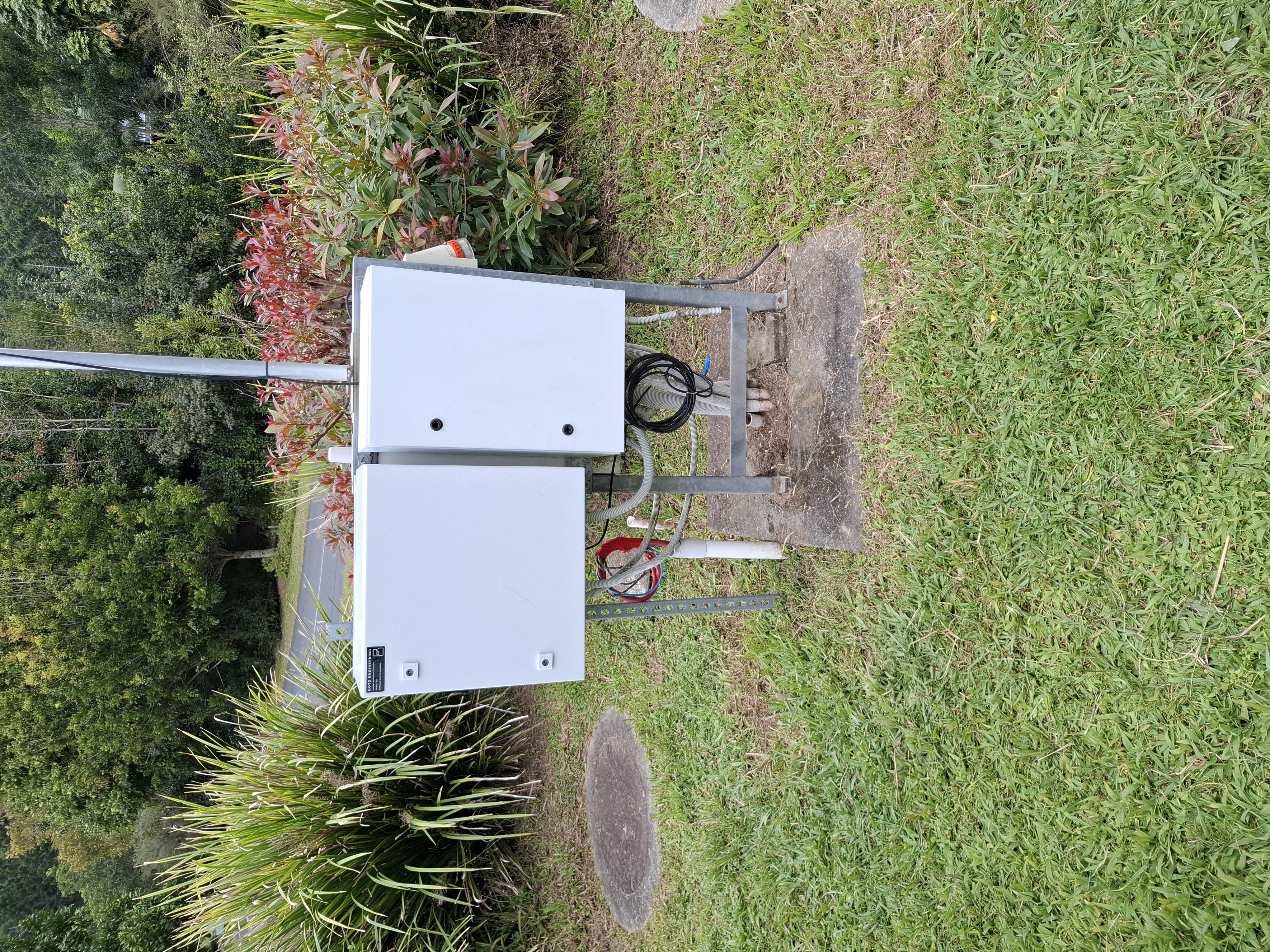 Commissioning the telemetry panel on site — laptop on the closed Goto-built enclosure, Flygt FGC323 visible in the open cabinet beside