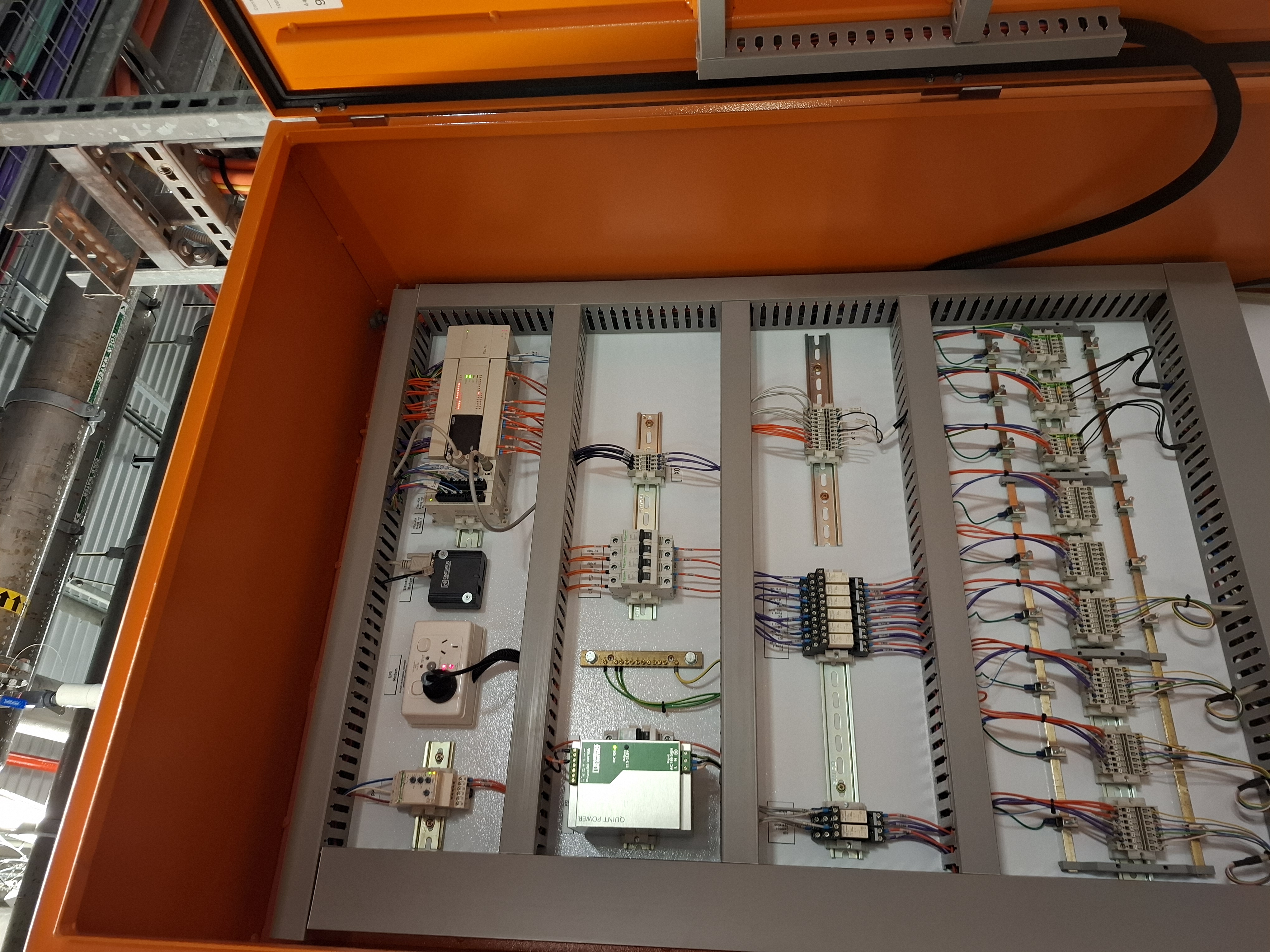 Potable water pump station control panel internal — Mitsubishi PLC, cellular modem, 24V supply and terminal strip layout
