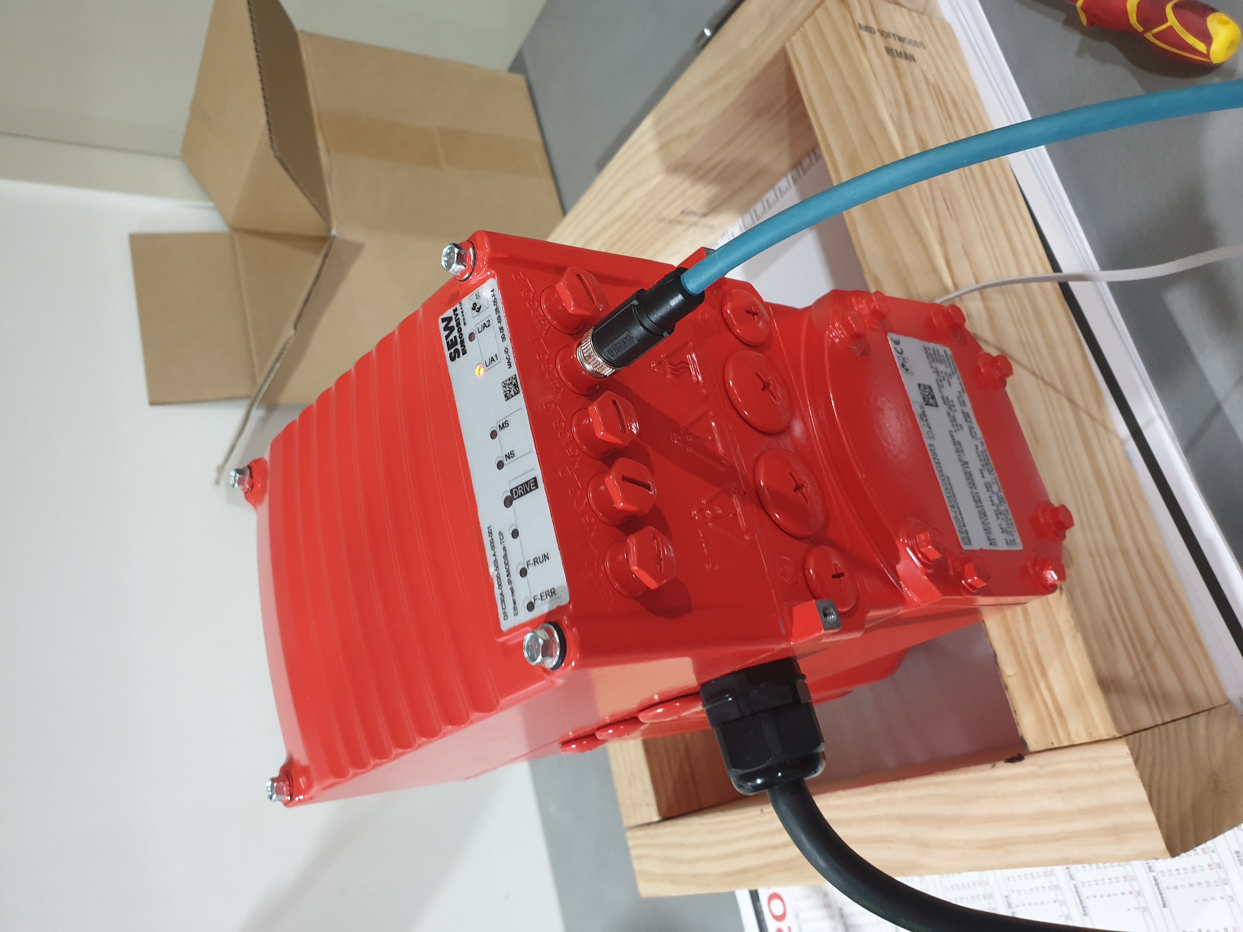 First-generation SEW Movigear DFC30A drive unit on a workbench, EtherNet/IP and M12 cables connected for R&D testing